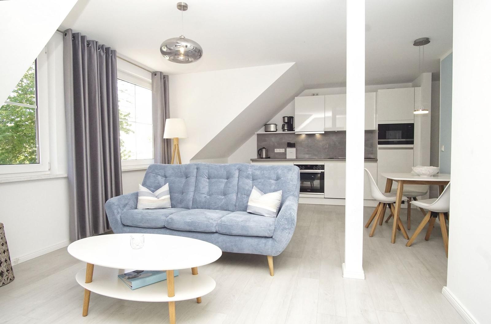 Wohnbereich mit Sofa, Couchtisch und Blick in die Küche