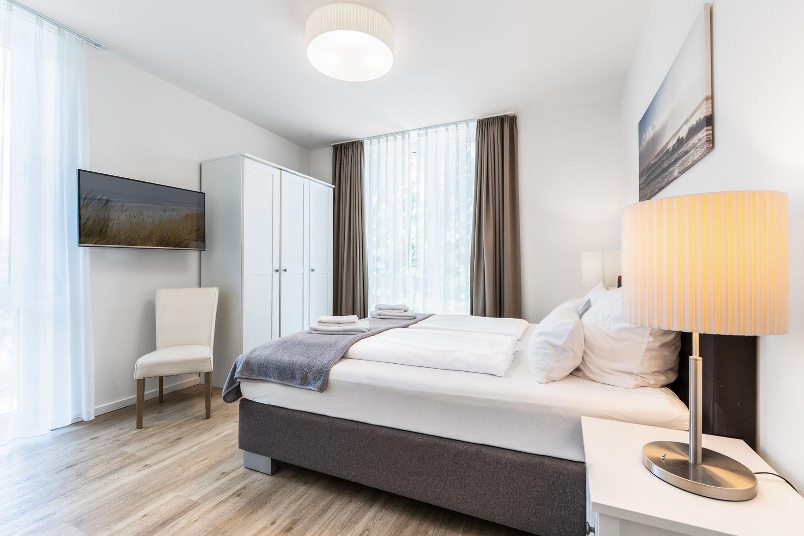 Schlafzimmer mit Doppelbett, Schrank, TV und Lampe.