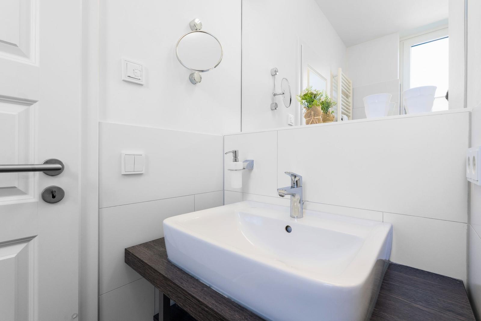 Bad mit Waschbecken auf Holzunterlage, Spiegel und Handtuchhalter