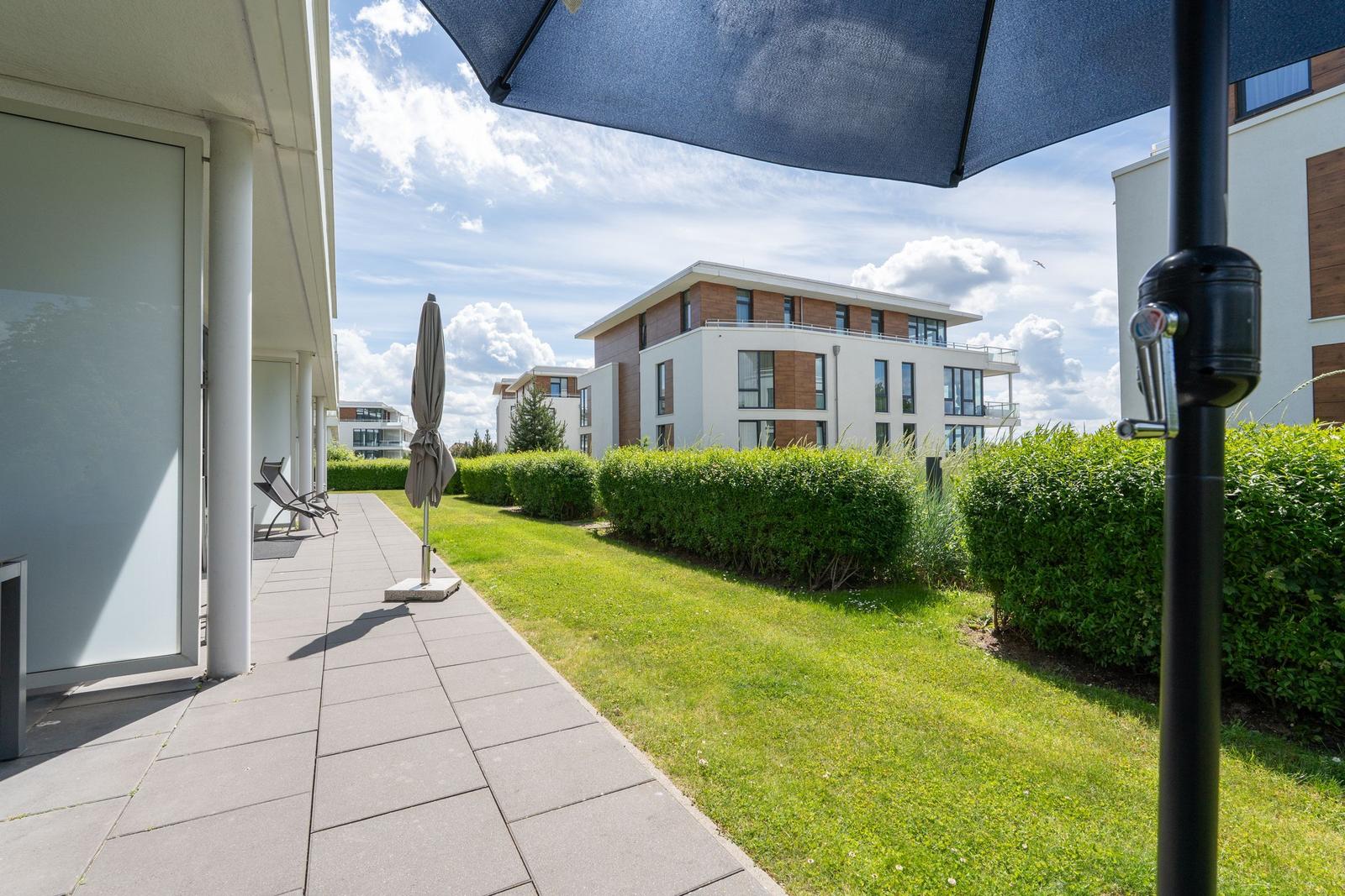 Terrasse mit Sonnenschirm und Blick auf moderne Wohnhäuser.