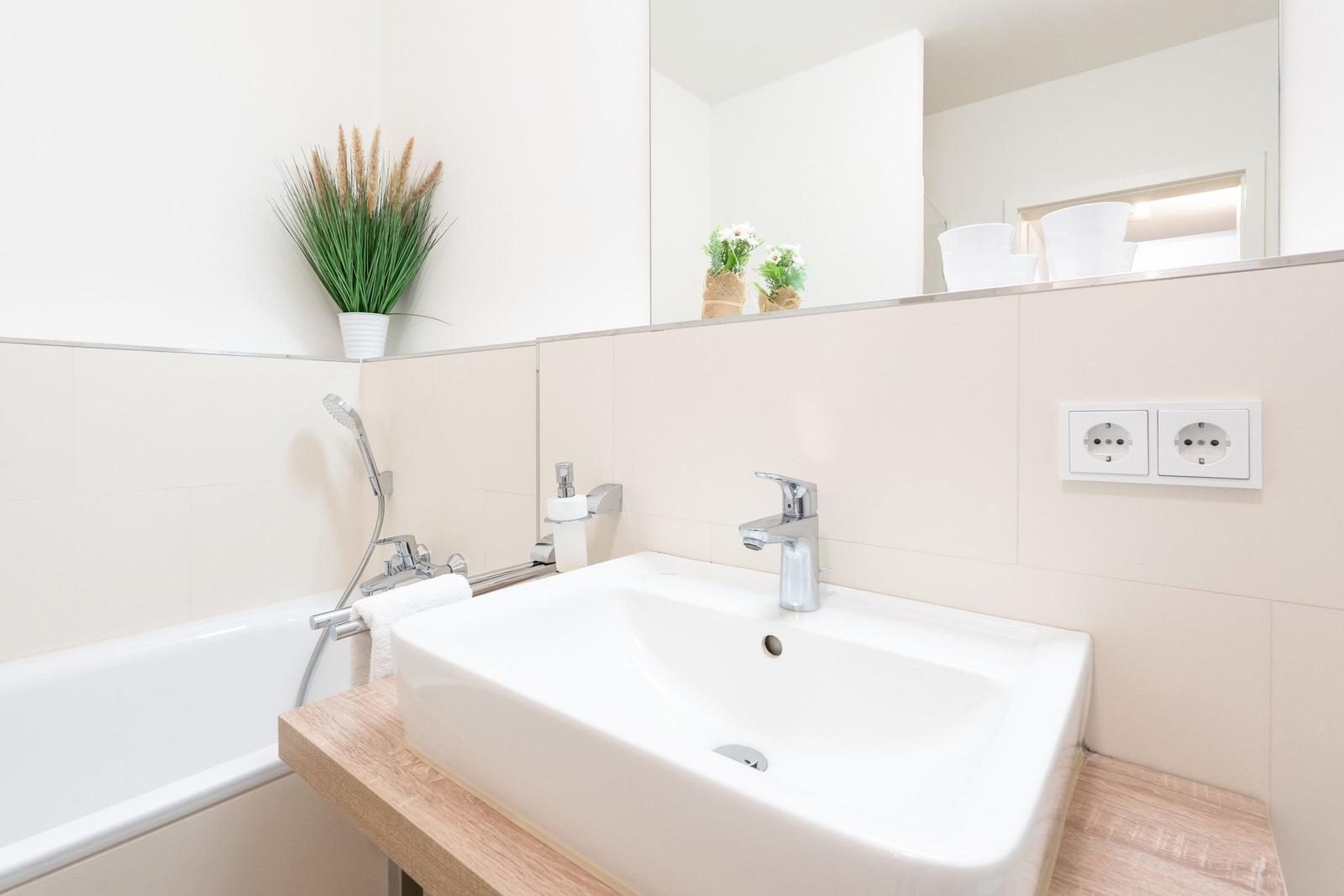 Bad mit Waschbecken, Dusche und Pflanze