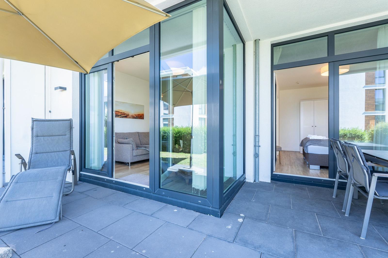 Terrasse mit Liege, Sitzgruppe und Blick in Wohn- und Schlafzimmer.
