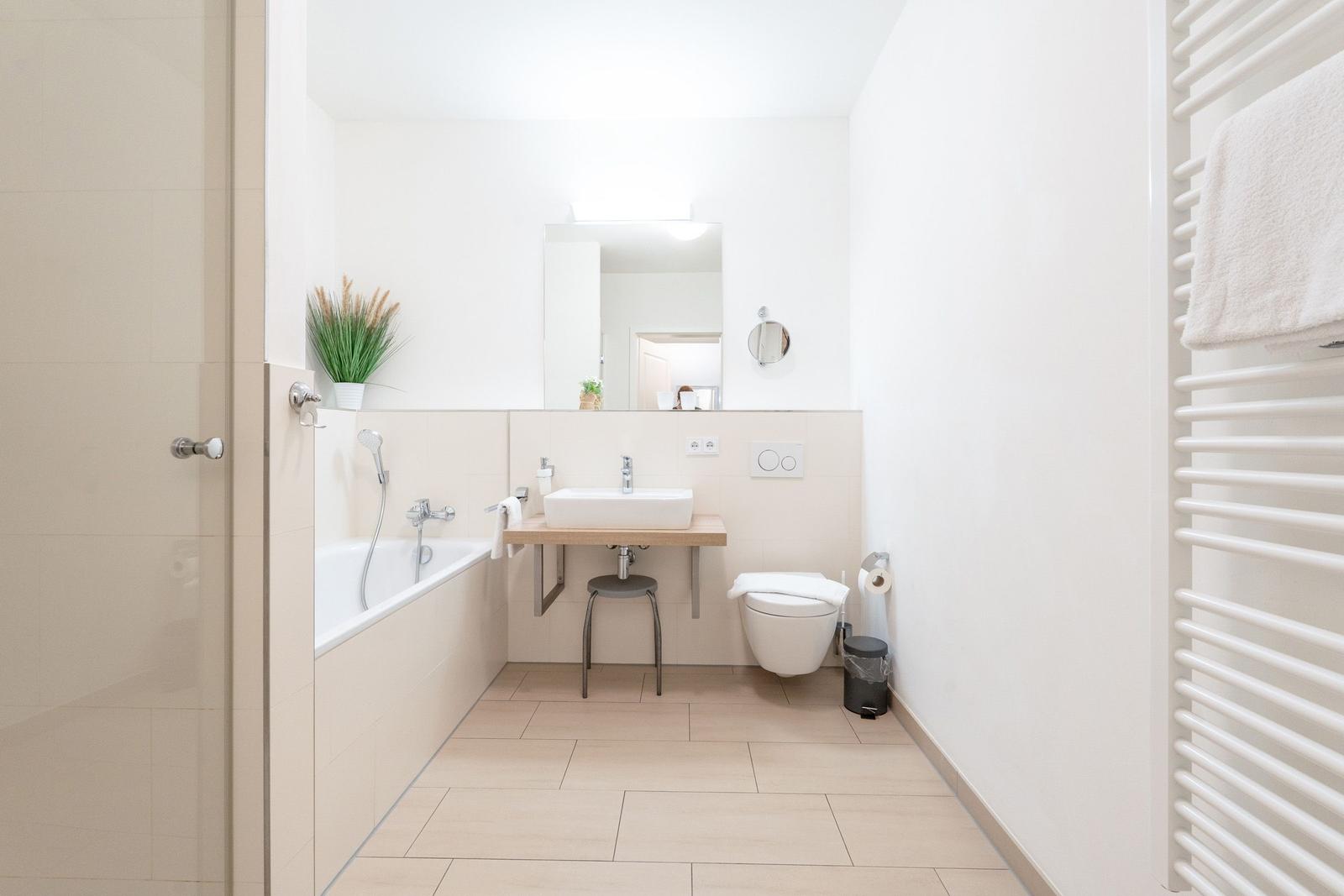 Badezimmer mit Badewanne, Waschbecken und Toilette. Warme Farbtöne und moderne Einrichtung.