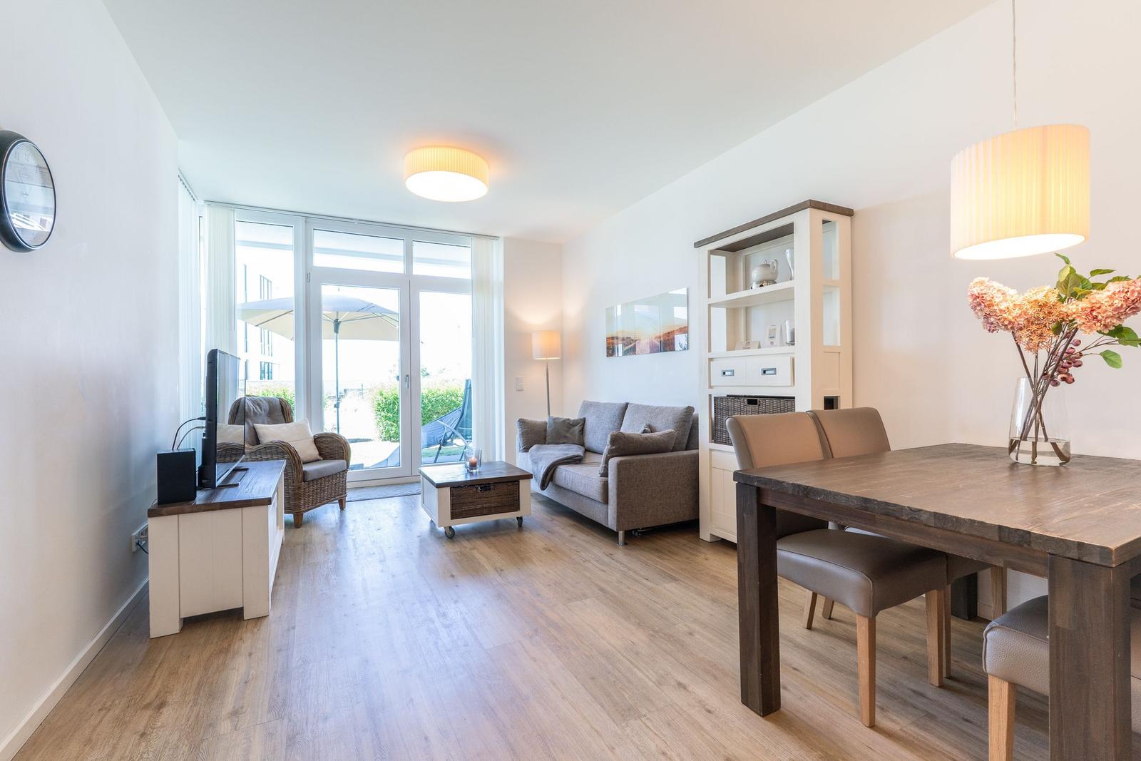 Wohn- und Essbereich mit Holzboden, Sofa, Esstisch und Blick auf die Terrasse.