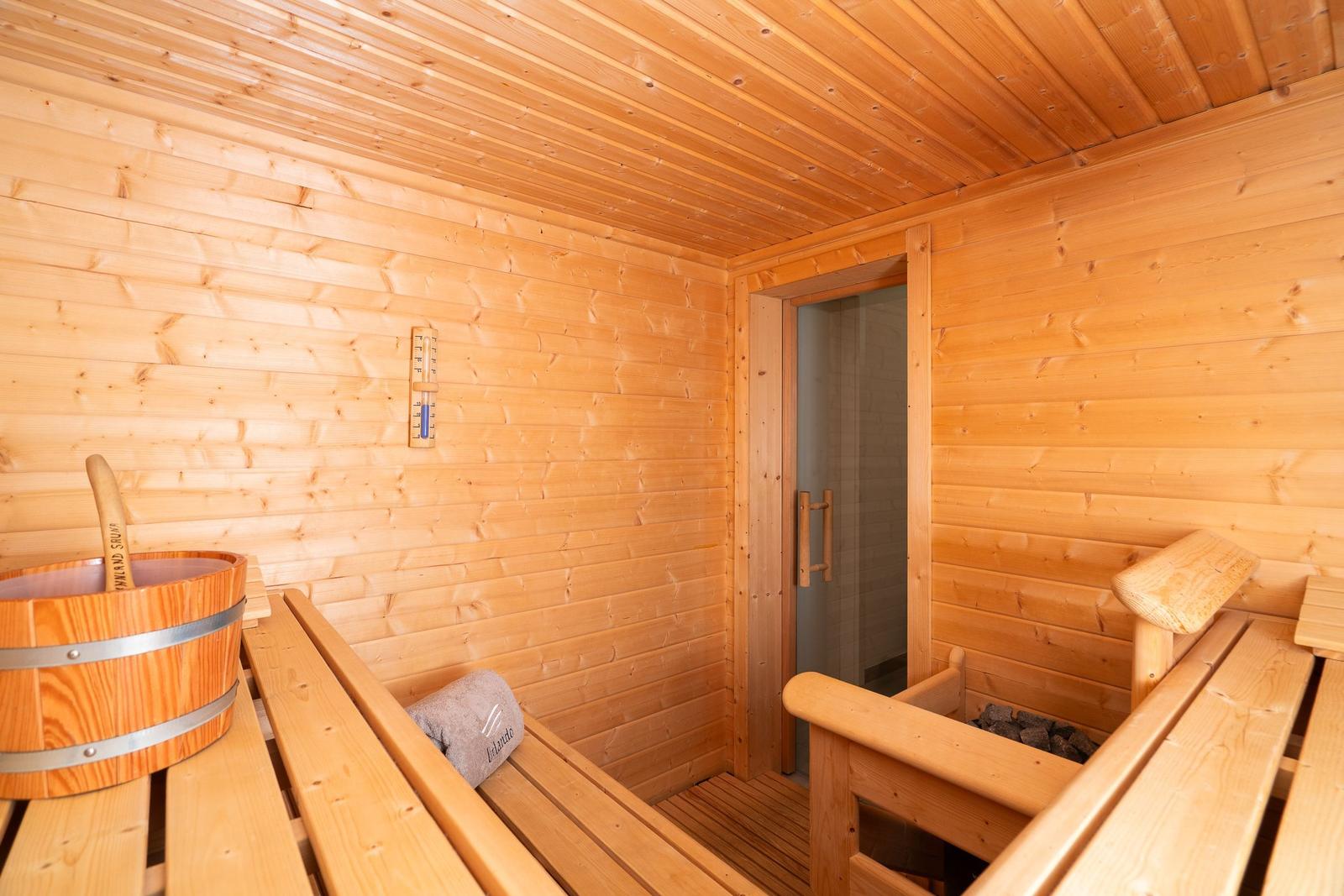 Sauna mit Holzbank, Eiche, Thermometer und Holzwanne.
