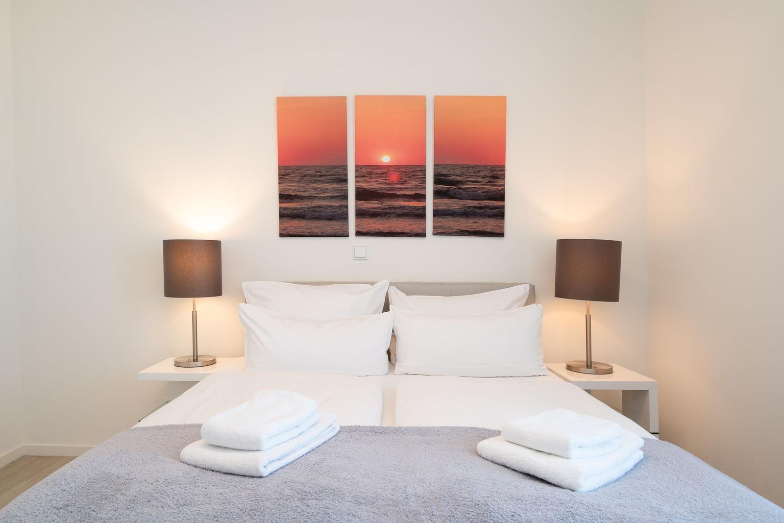 Schlafzimmer mit Bett, Nachttischen und Wandbildern
