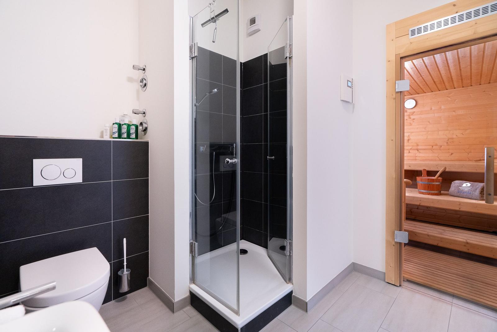 Bad mit Dusche und Sauna im Hintergrund
