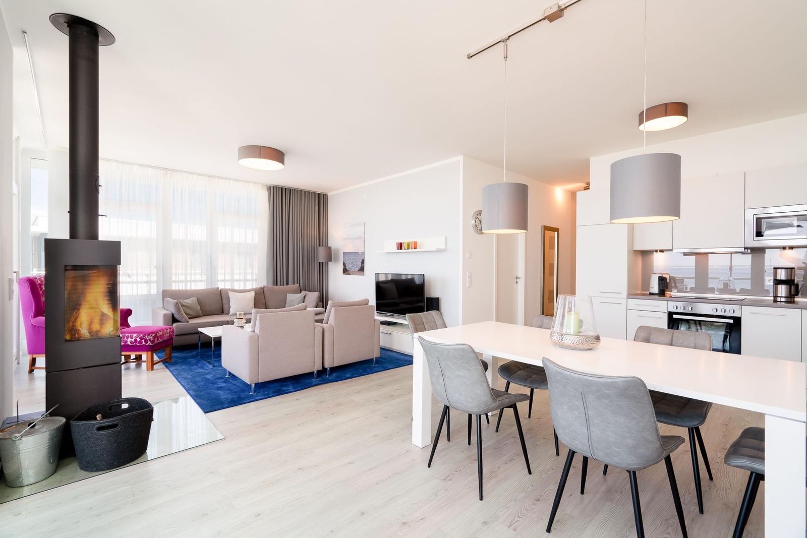 Wohn- und Essbereich mit Kamin, Sofa, Esstisch und moderner Küche.