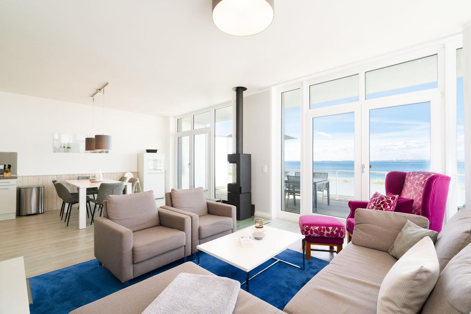 Wohnzimmer mit Sofa, Sessel und Blick aufs Meer.