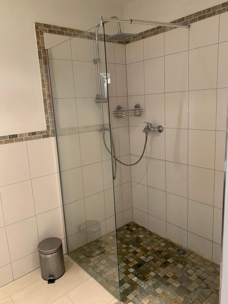 Dusche mit Glaswand, Mosaikboden und Duschbrause