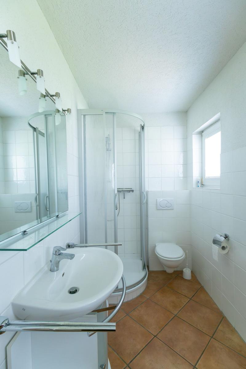 Badezimmer mit Dusche, Toilette und Waschbecken mit Spiegel