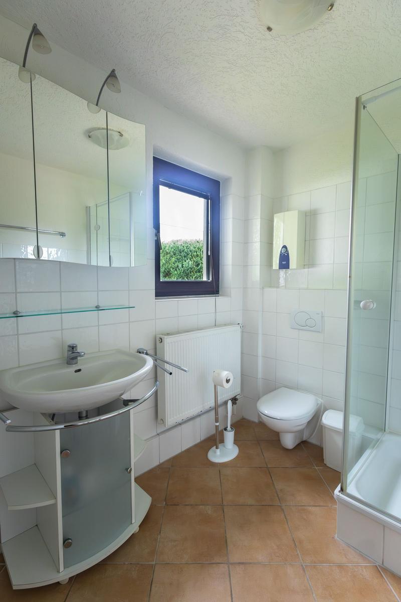 Badezimmer mit Dusche, Toilette und Waschbecken mit Spiegel.
