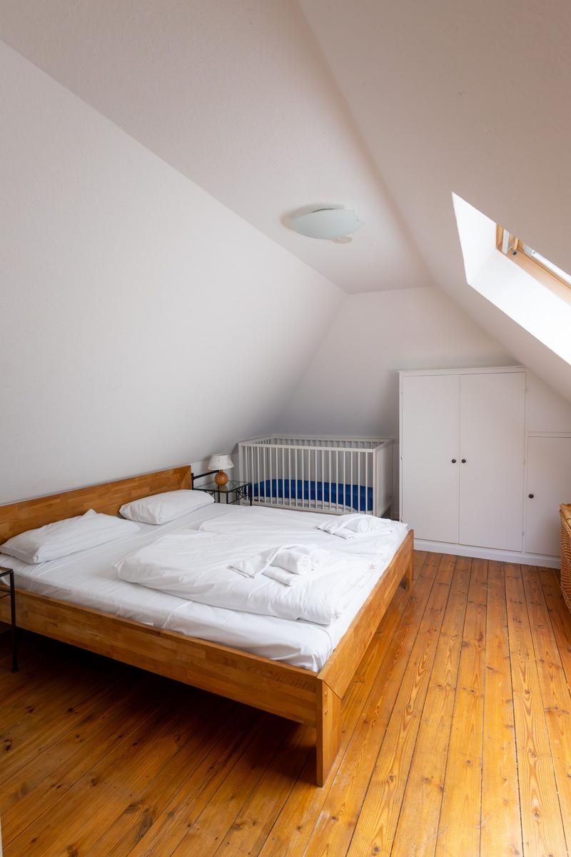 Schlafzimmer mit Doppelbett, Kinderbett und Kleiderschrank unter Dachschrägen.