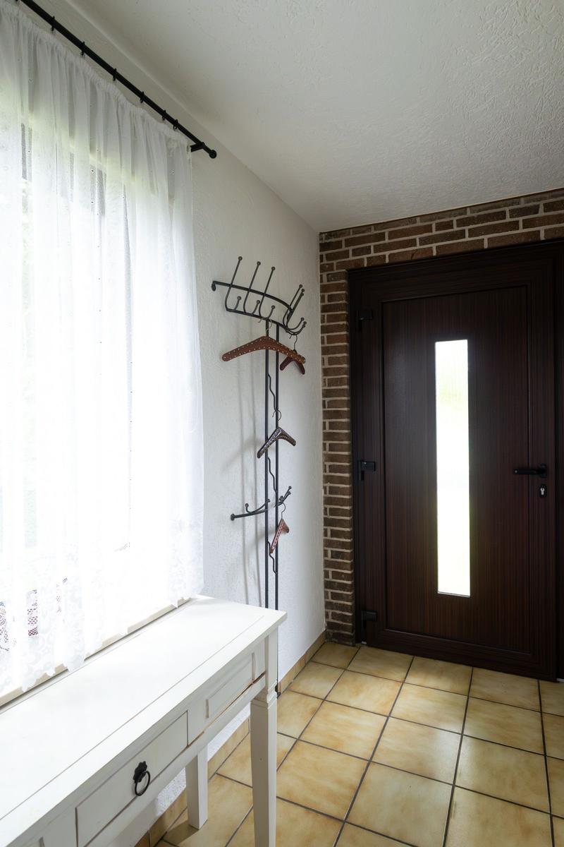 Eingangsbereich mit Tür, Garderobe und Fenster mit Vorhängen.