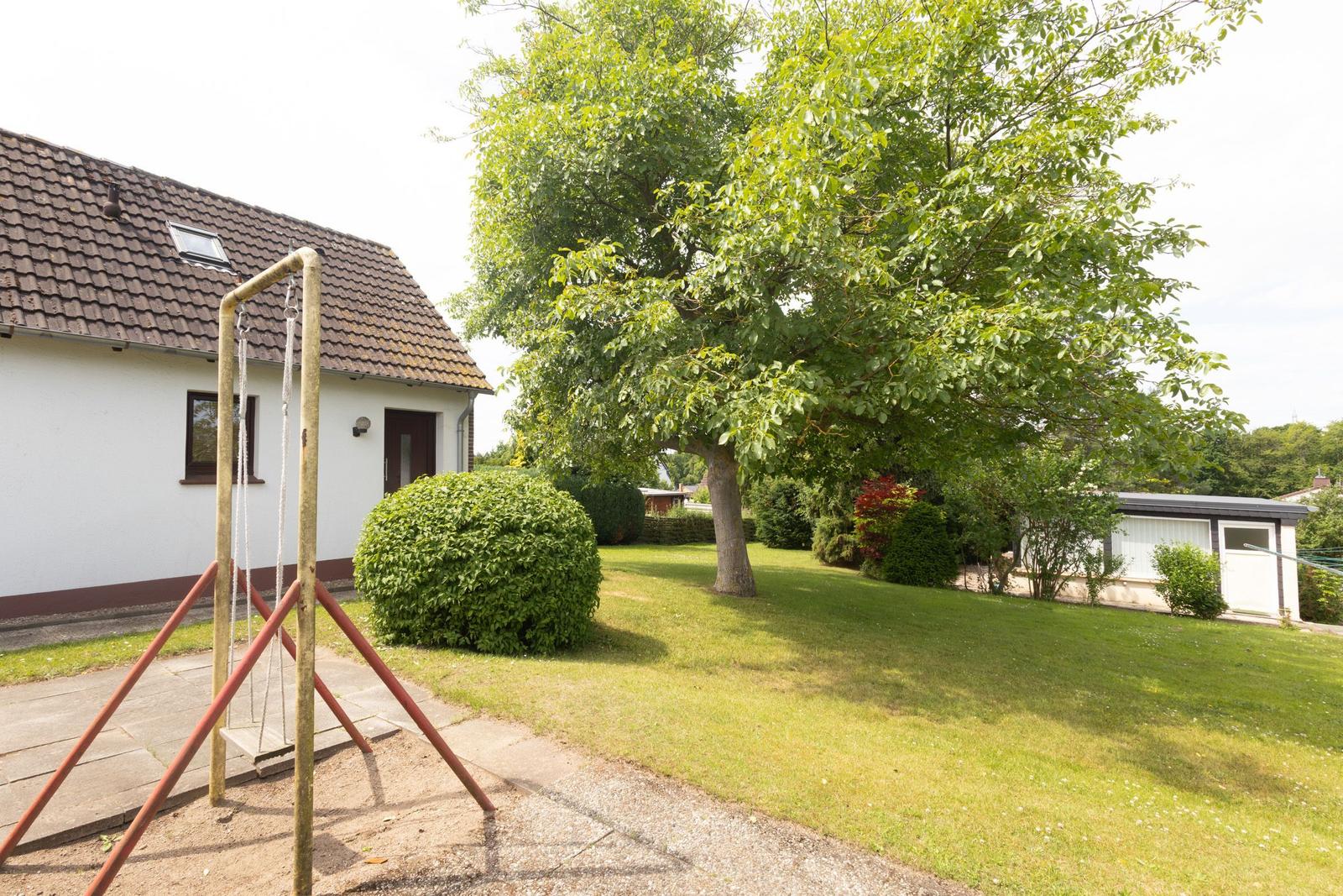 Haus mit Garten, Spielplatz und Baum.