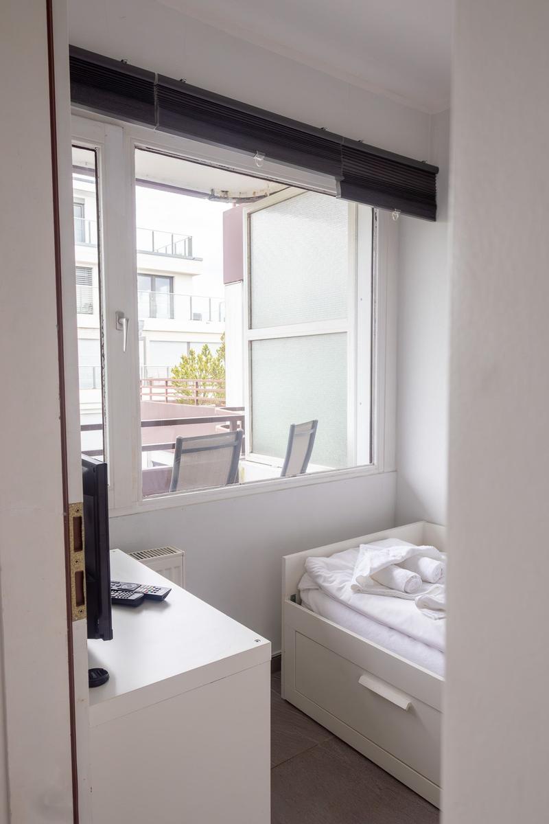 Schlafzimmer mit Bett, Schreibtisch und Fenster zur Terrasse.
