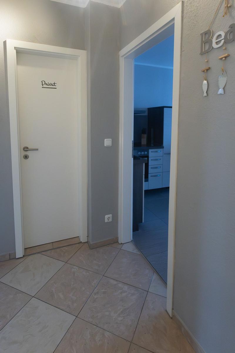Flur mit Tür zur privaten Wohnung und Blick in die Küche.