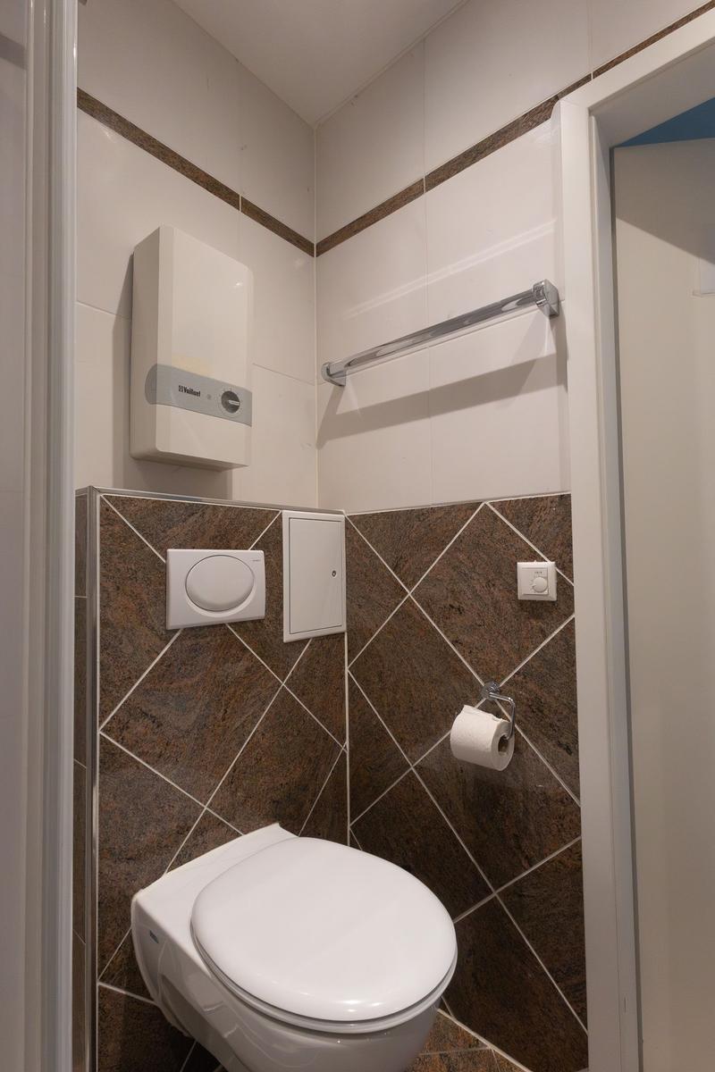 Badezimmer mit Toilette, Handtuchhalter und Heizung.