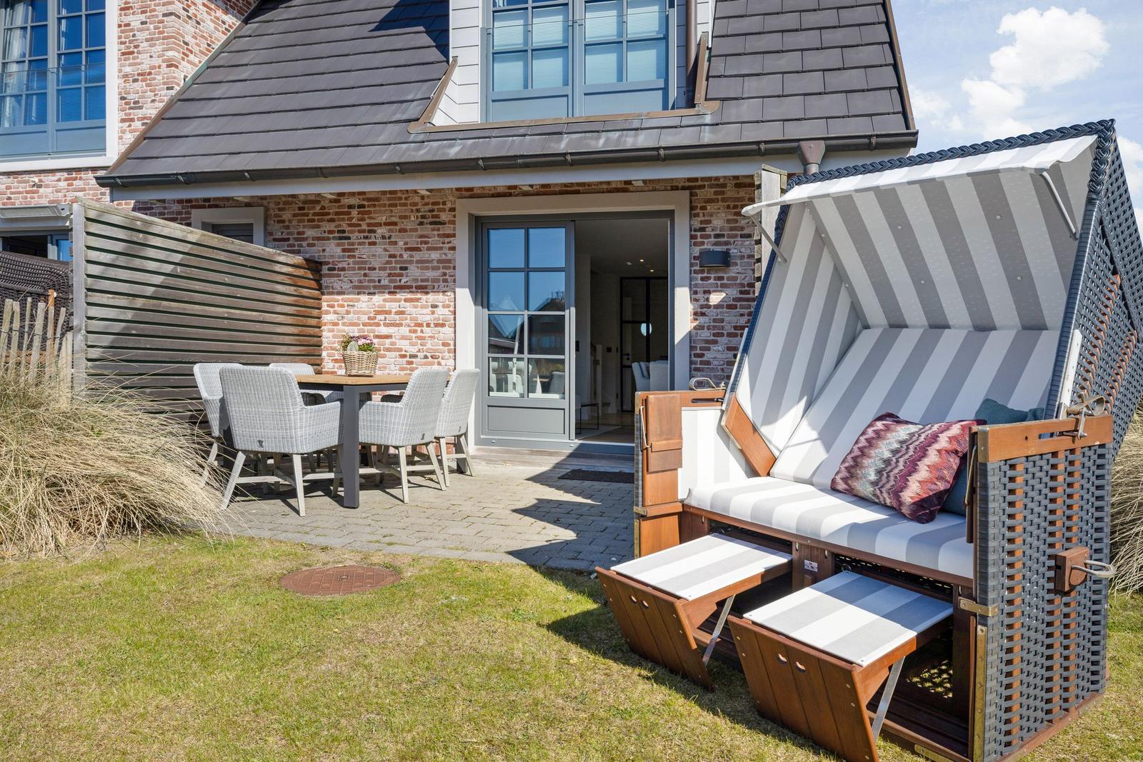 Hinterhof mit Garten, Terrasse, Tisch, Stühlen und Strandkorb.