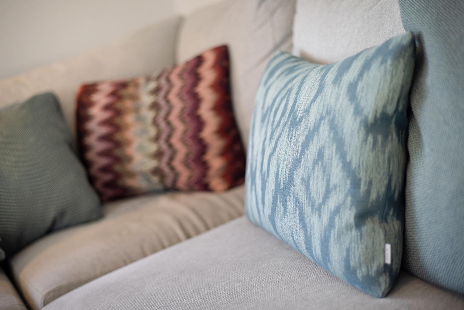 Ein Sofa mit mehreren Kissen in verschiedenen Mustern und Farben.