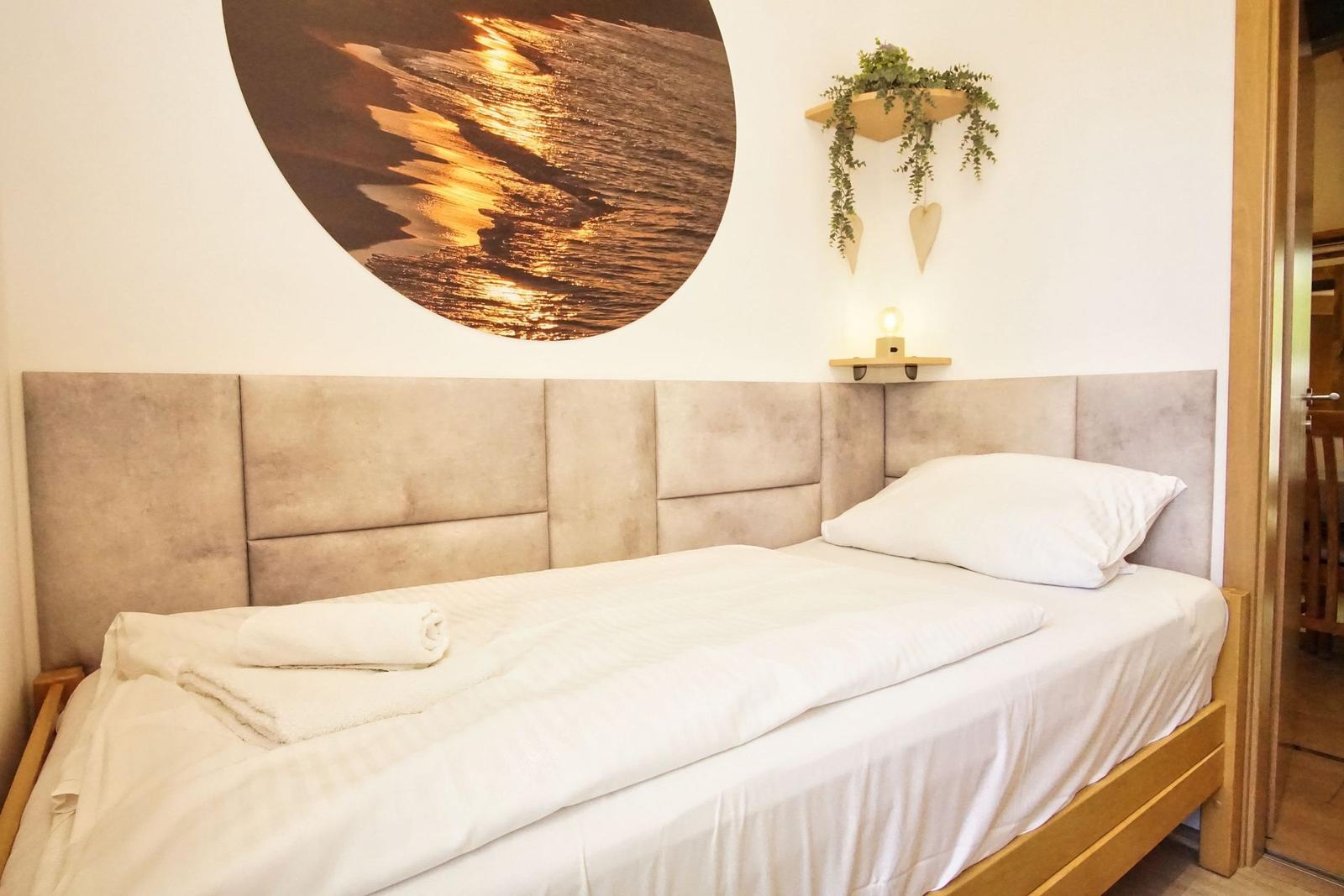 Ein Bett mit weißer Bettwäsche und einem runden Wandbild über dem Kopfteil.