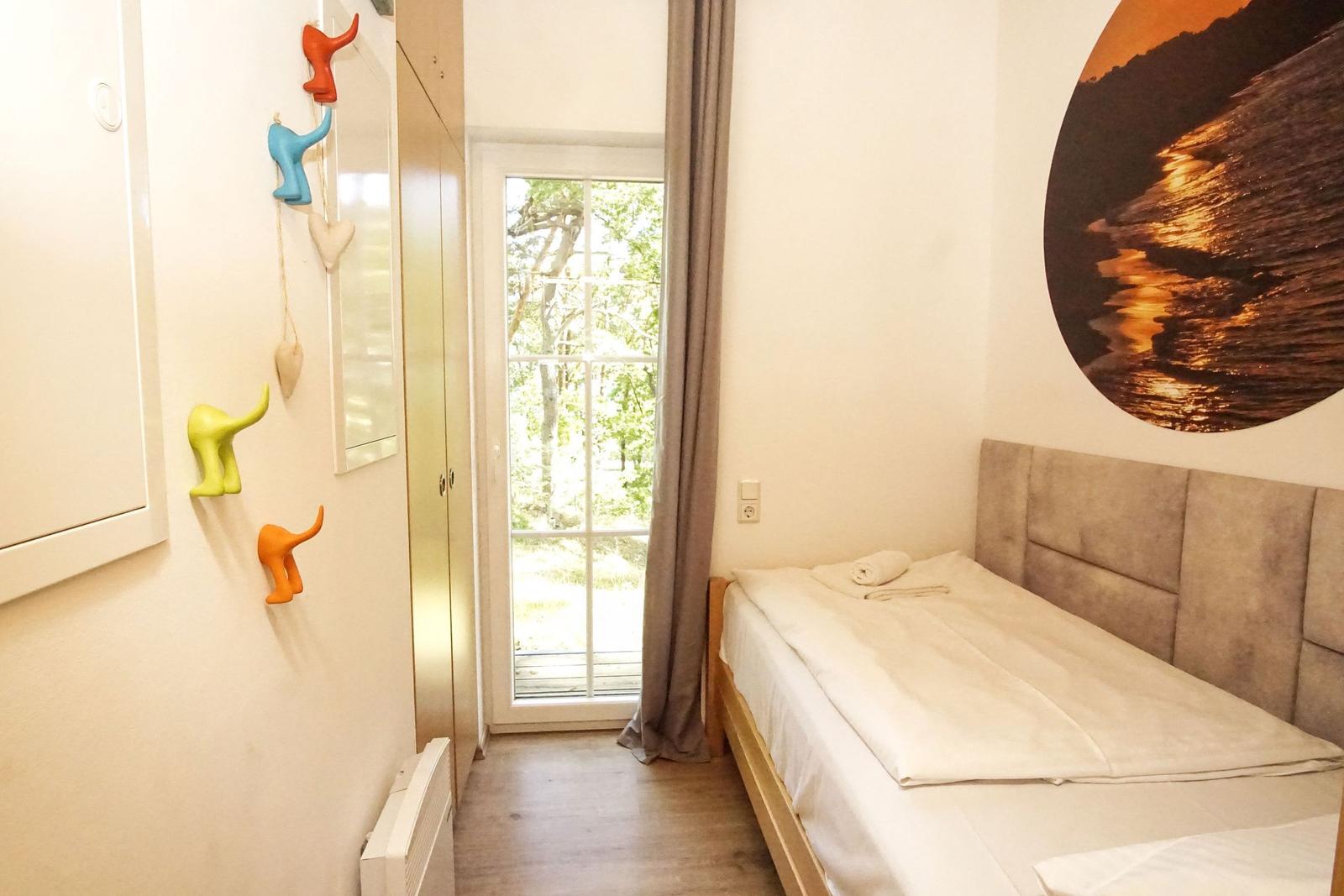 Schlafzimmer mit Bett, Fenster und Wandbild. Wanddekoration mit bunten Figuren.