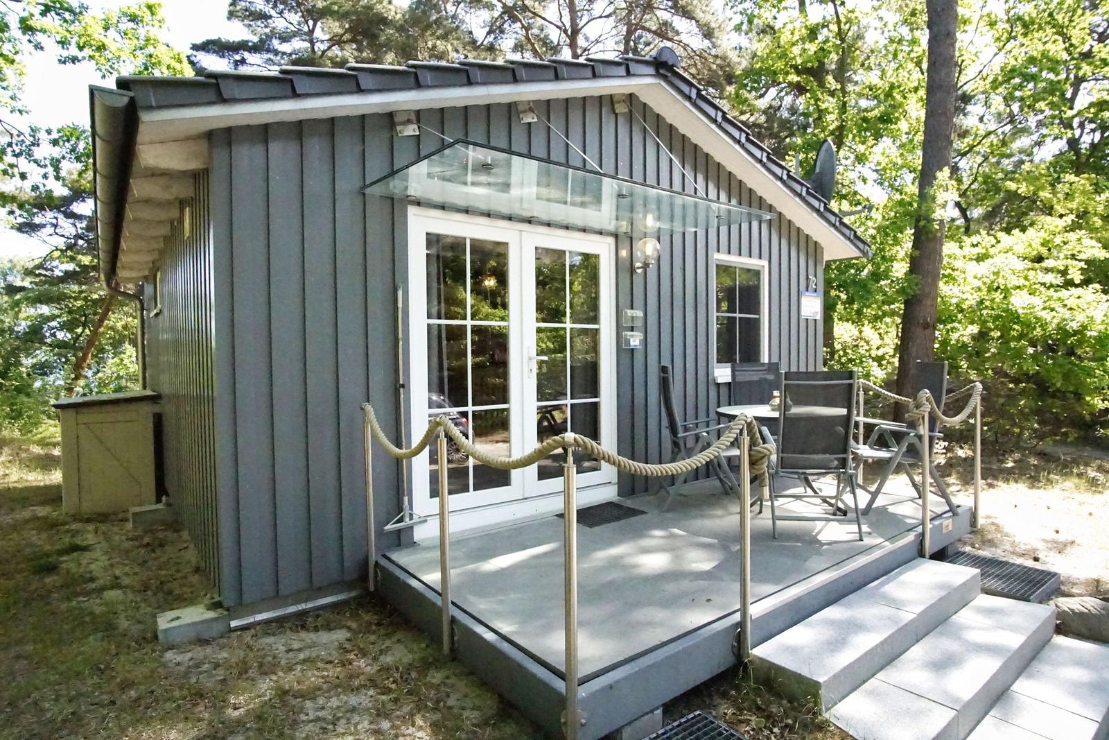 Moderne Hütte mit Terrasse, Sitzgelegenheiten und Glasüberdachung im Wald