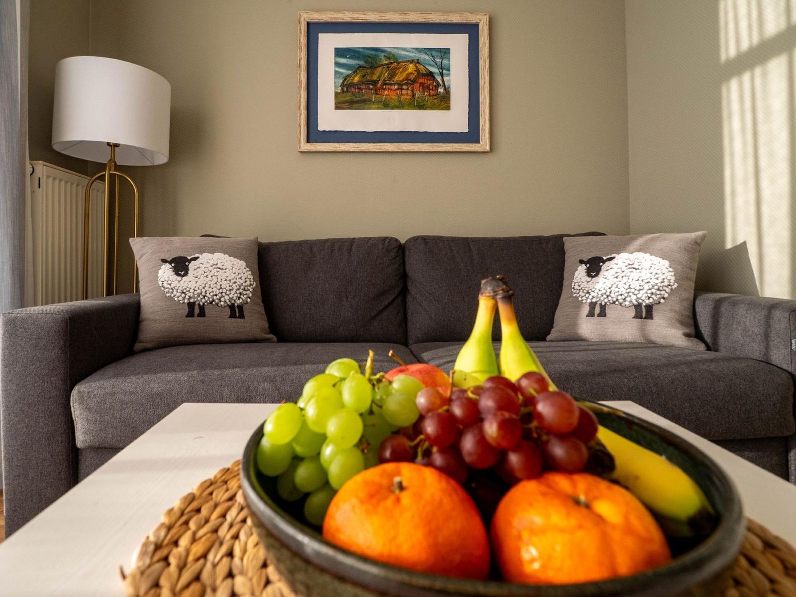 Ein Sofa mit Schafkissen und Obstschale auf Tisch