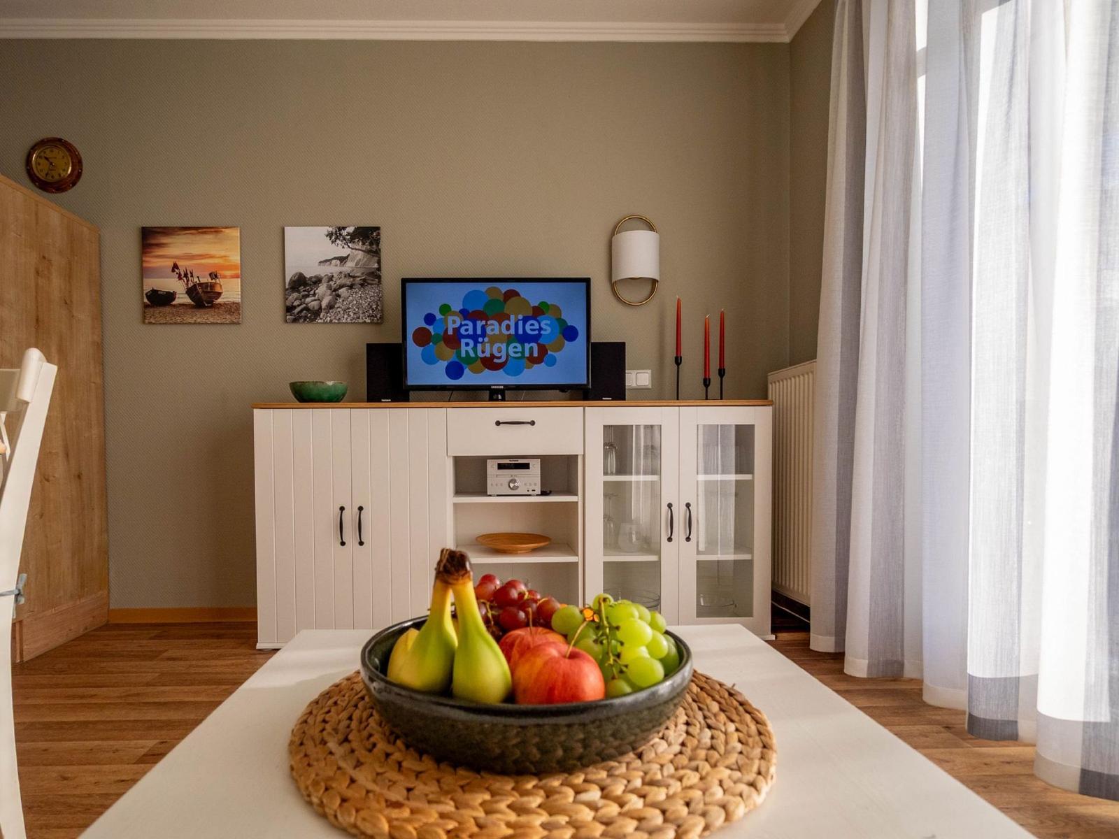 Ein Essbereich mit Obstschale, Fernseher und Bildern an der Wand.
