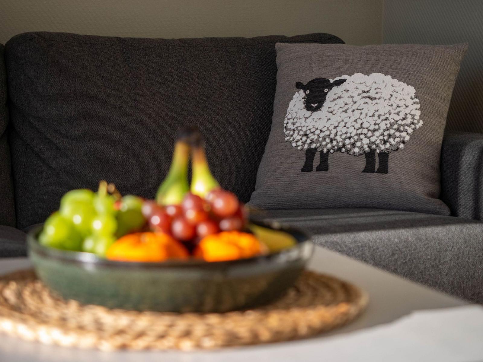 Ein grauer Sofa mit Kissen und Obstschale auf Tisch