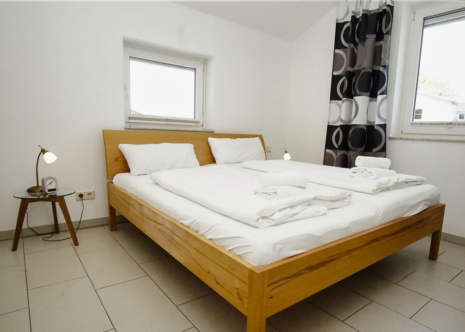 Ein Schlafzimmer mit einem Holzbett, weißen Laken und einem Nachttisch mit Lampe.