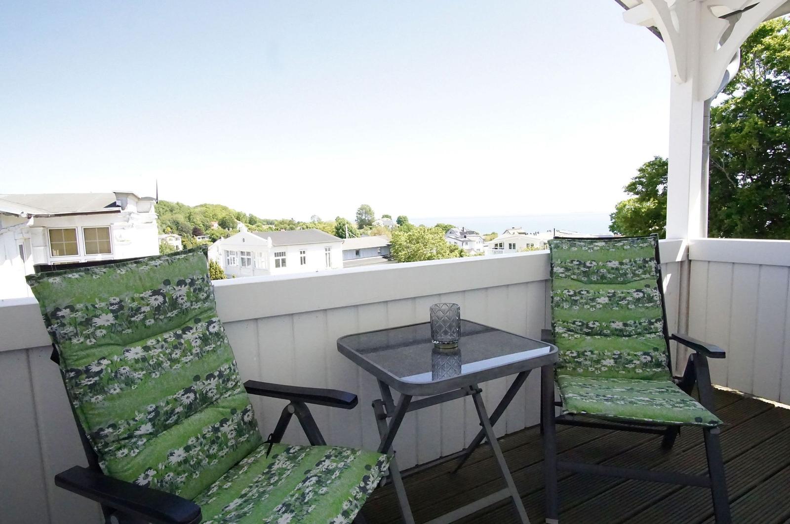 Terrasse mit zwei Stühlen und Tisch. Blick auf Häuser und Meer.