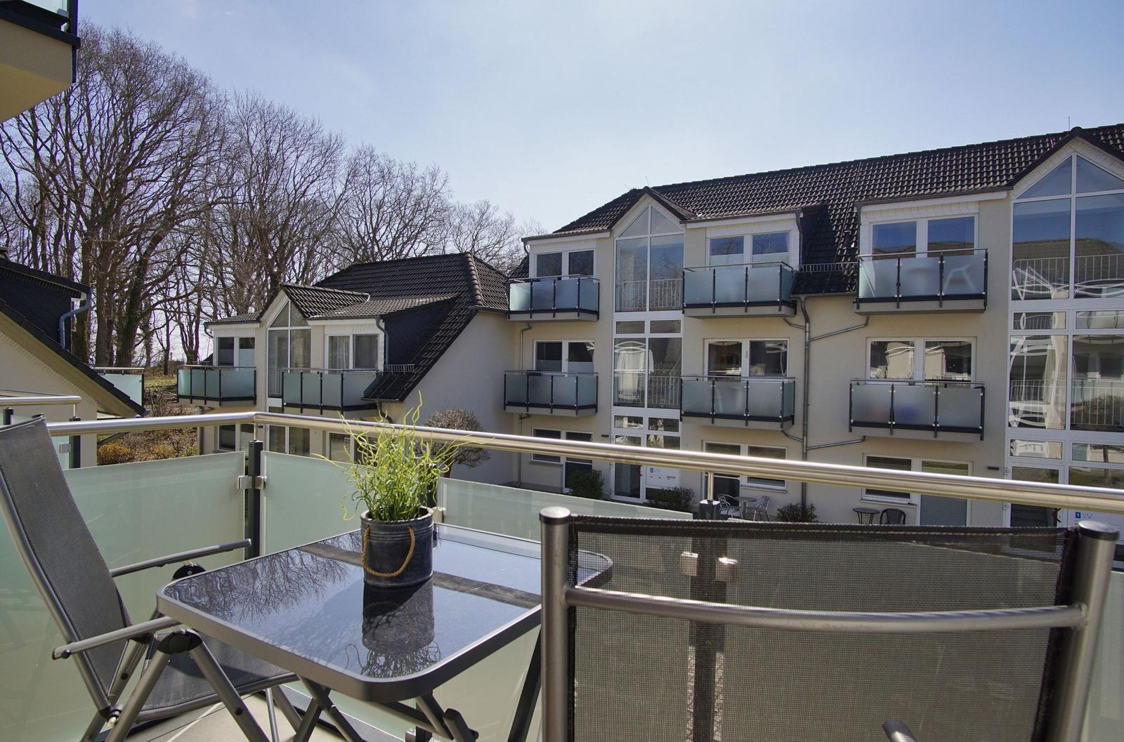 Terrasse mit Tisch und Stühlen, Blick auf Wohnhaus mit Balkonen.