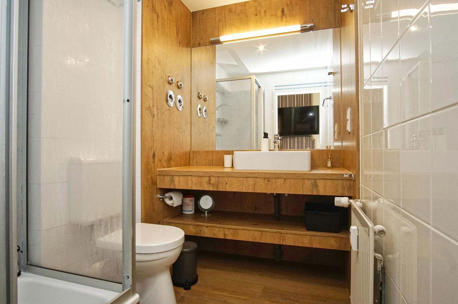 Badezimmer mit Holzwand, Waschtisch und Dusche
