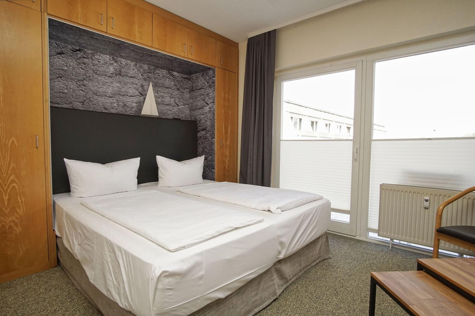 Schlafzimmer mit Doppelbett, Holzmöbel und Fenster mit Blick.