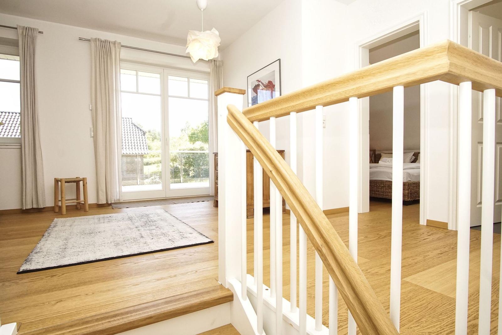 Haus mit Holzstufen, weißen Geländern und Blick auf Schlafzimmer und Terrasse.