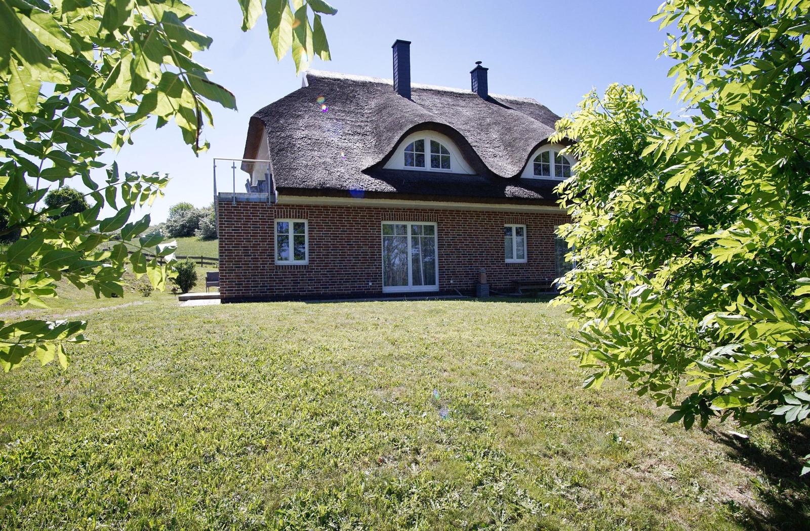 Haus mit Strohdach, Backsteinfassade und Garten
