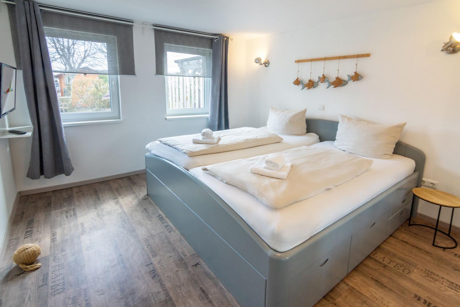 Schlafzimmer mit Doppelbett, Fenstern und Holzboden