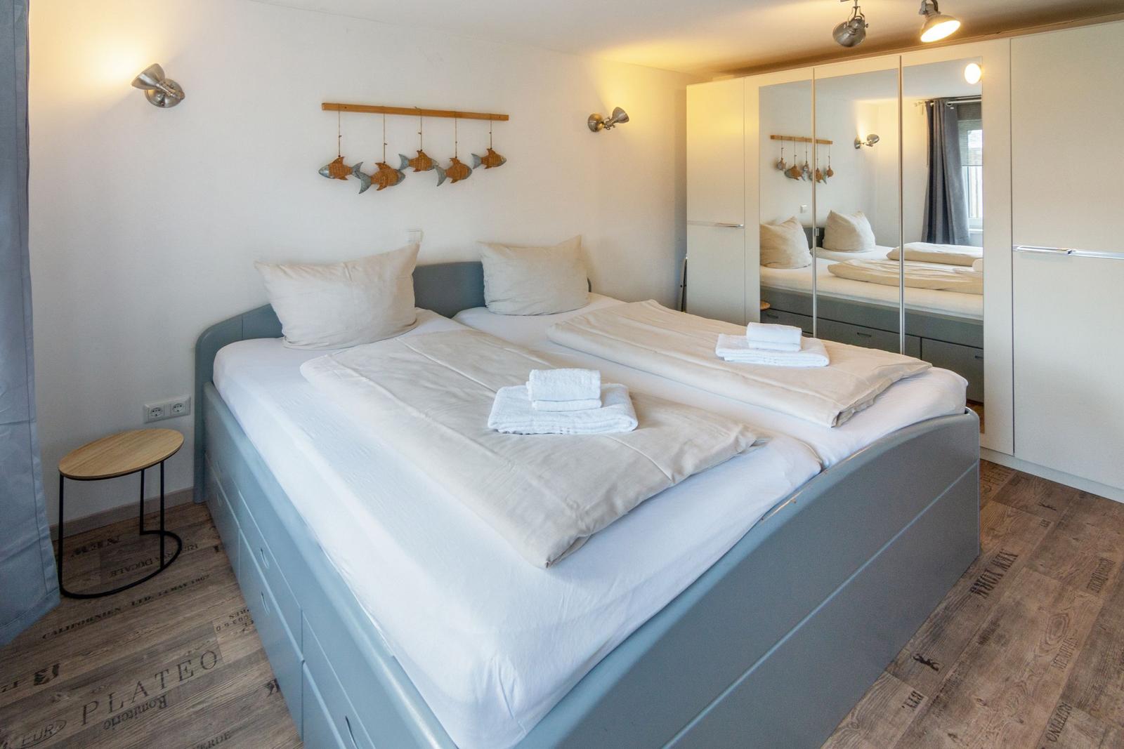 Schlafzimmer mit Doppelbett, Spiegelschrank und Holzboden
