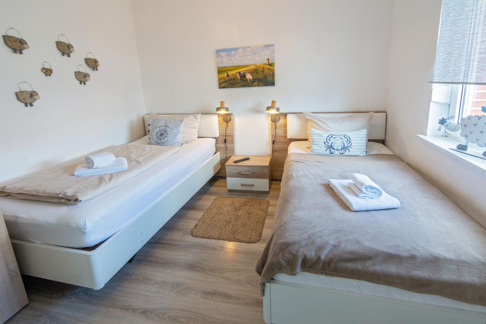 Zwei Einzelbetten mit Bettwäsche, Wandbild und Nachttisch im Schlafzimmer.