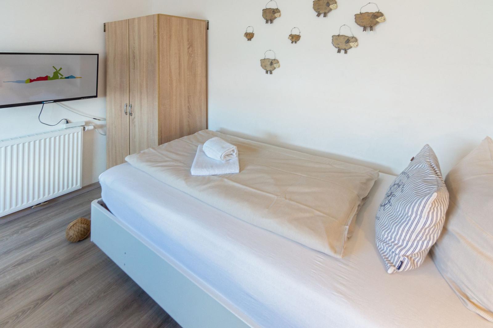Schlafzimmer mit Bett, Kleiderschrank und Wanddekoration