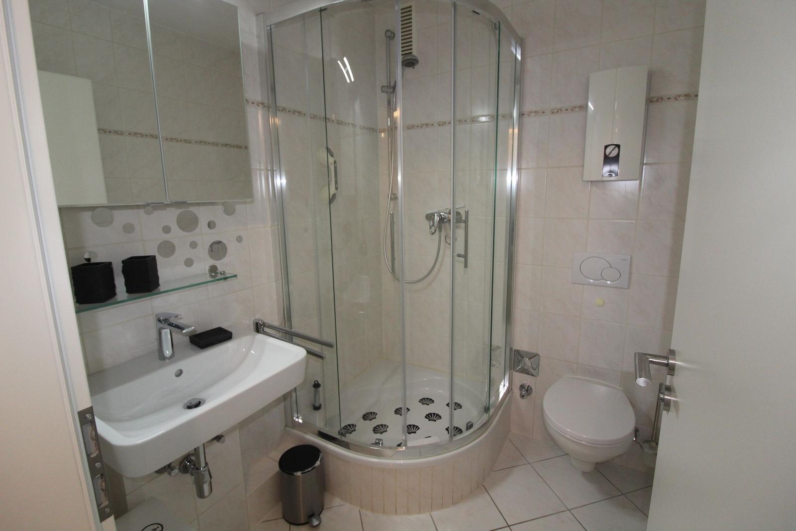 Badezimmer mit Dusche, Waschbecken und Toilette.