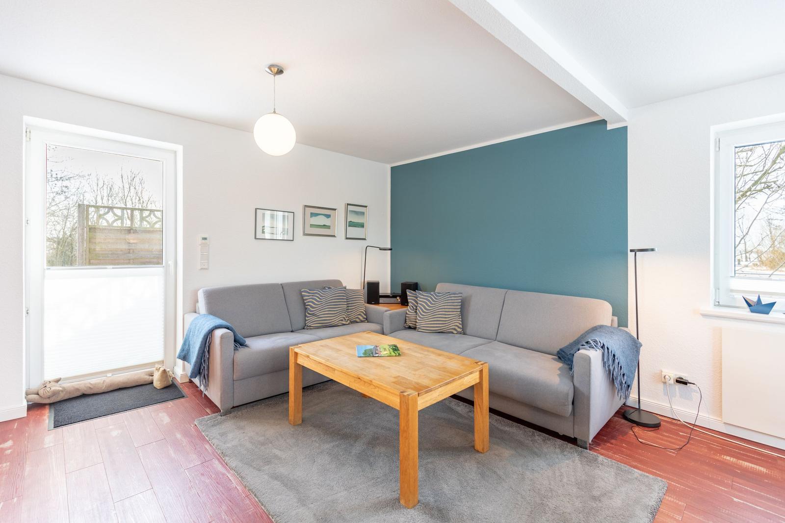 Wohnzimmer mit grauem Sofa, Holztisch und blauer Wand