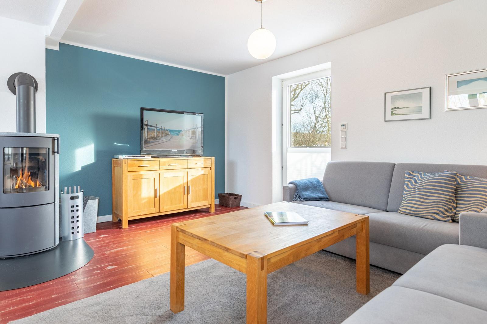 Wohnzimmer mit Sofa, Kamin, Fernseher und Holztisch.