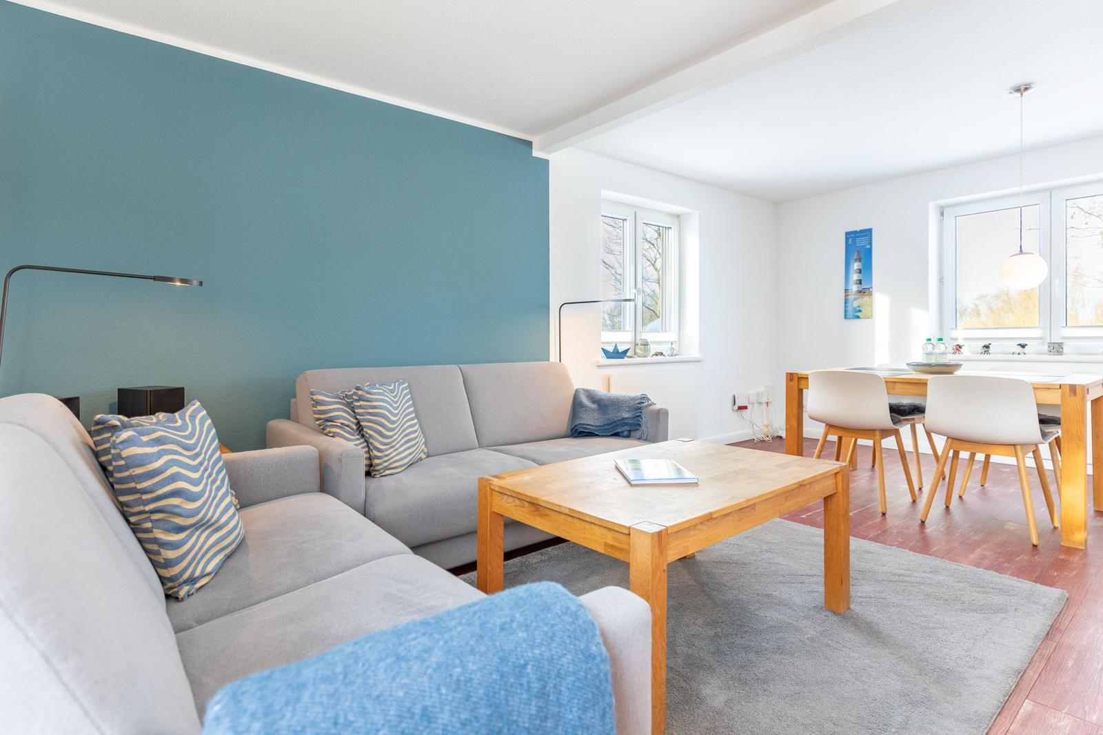 Wohn- und Essbereich mit Sofa, Tisch und Stühlen. Wand in Blau.