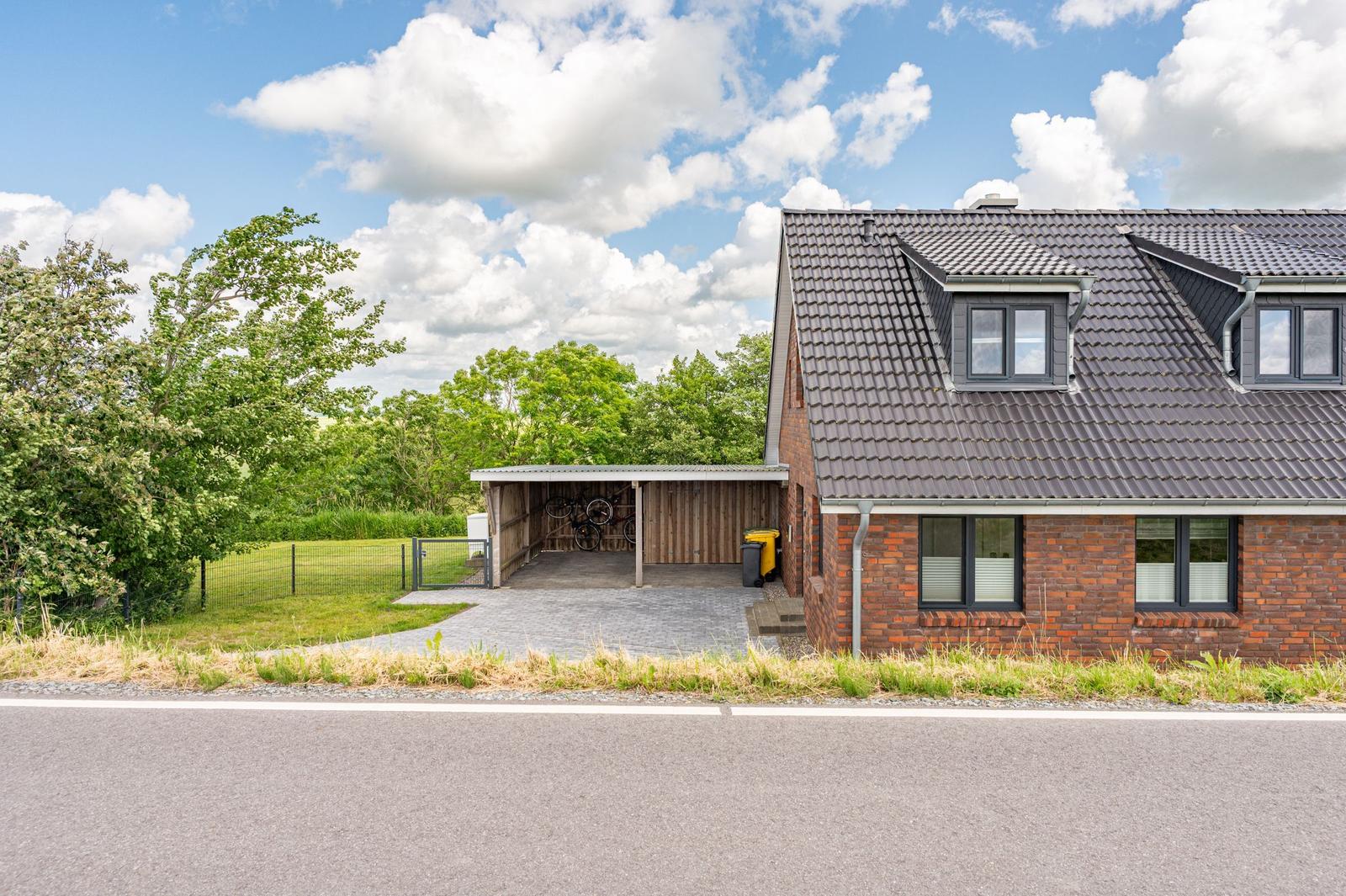Ein Haus mit Backsteinfassade, Dachgauben und einer Garage mit Fahrrädern.