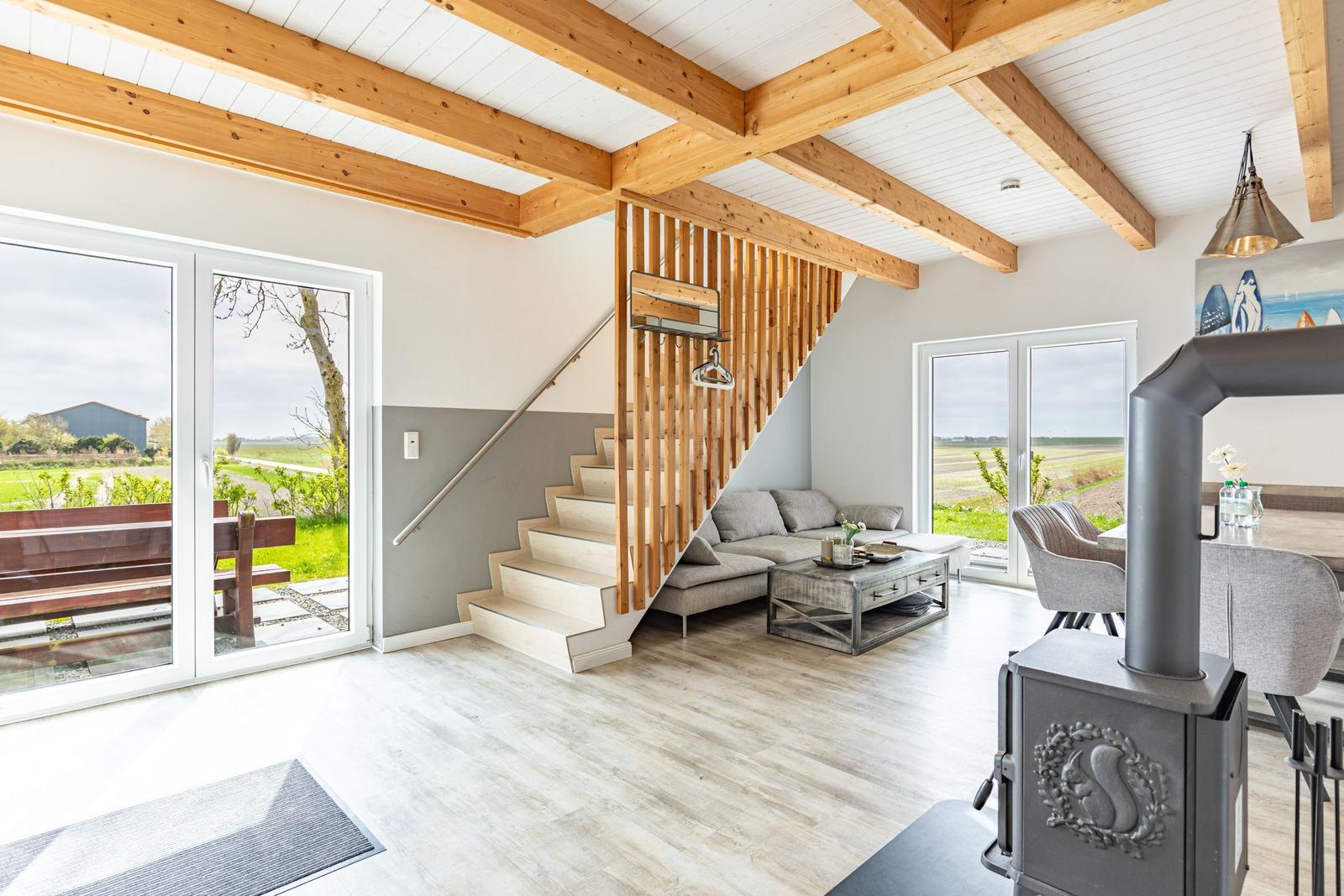 Wohnbereich mit Holzdecke, Treppenhaus und Blick auf die Landschaft.