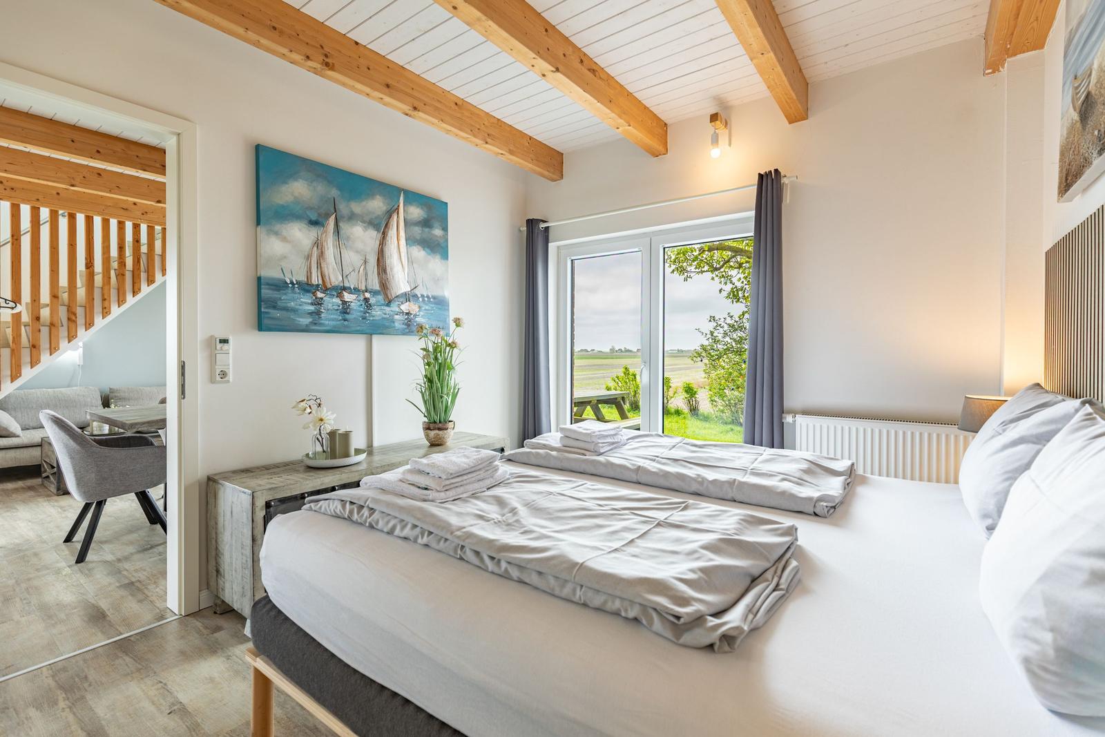 Schlafzimmer mit Doppelbett, Blick auf Grünland und Gemälde an der Wand.