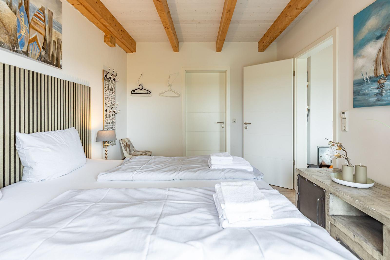 Zimmer mit Doppelbett, Holzbalkendecke und Wandbildern. Nebenraum ist sichtbar.