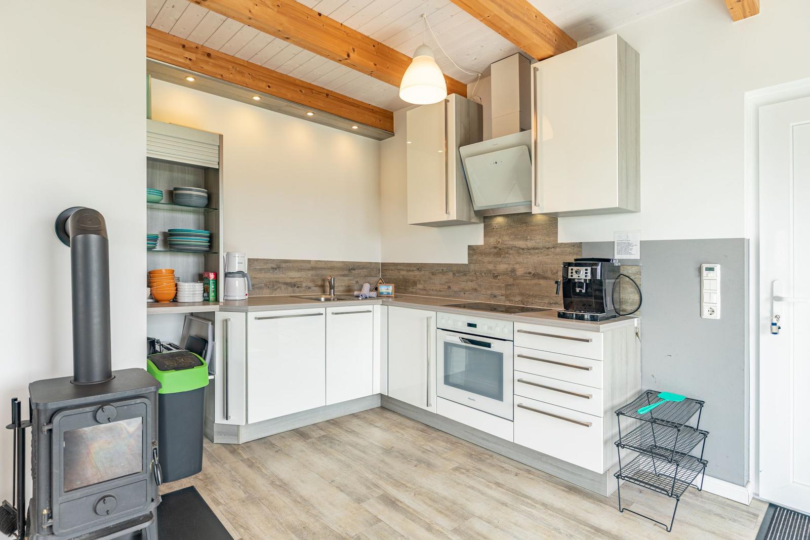 Küche mit weißen Schränken, Holzdielen und Holzbalken an der Decke.